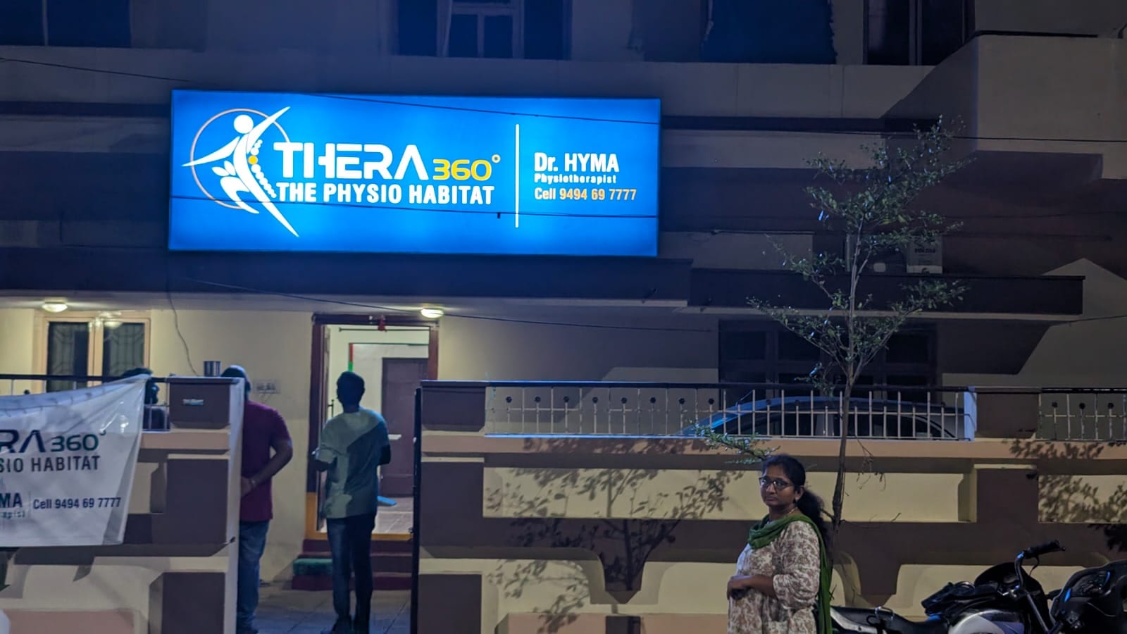 The illuminated Thera360 (The Physio Habitat) signboard lit up at night above the clinic entrance