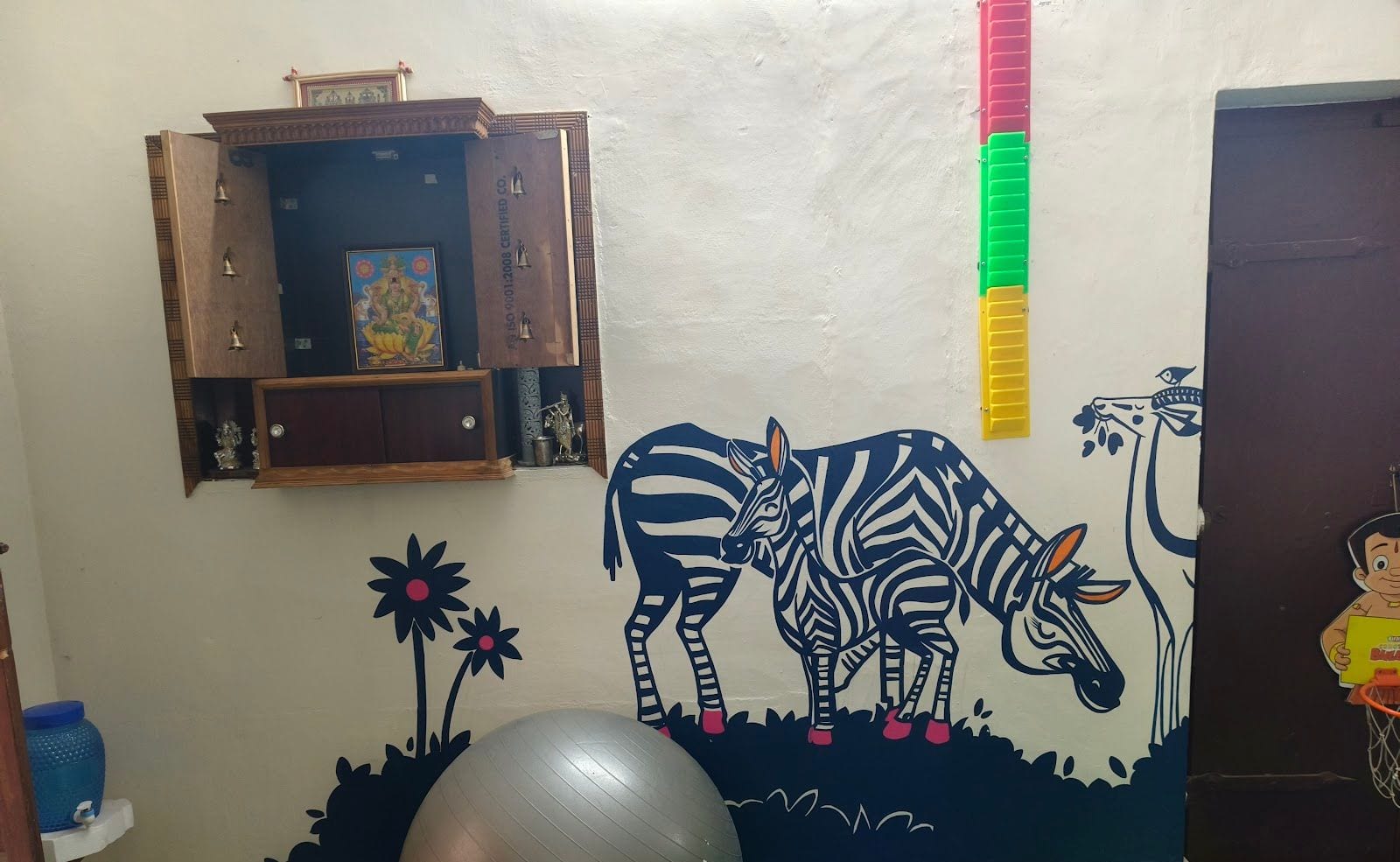 Pediatric therapy room with a zebra wall mural, a gym ball and a wall-mounted stepping ladder