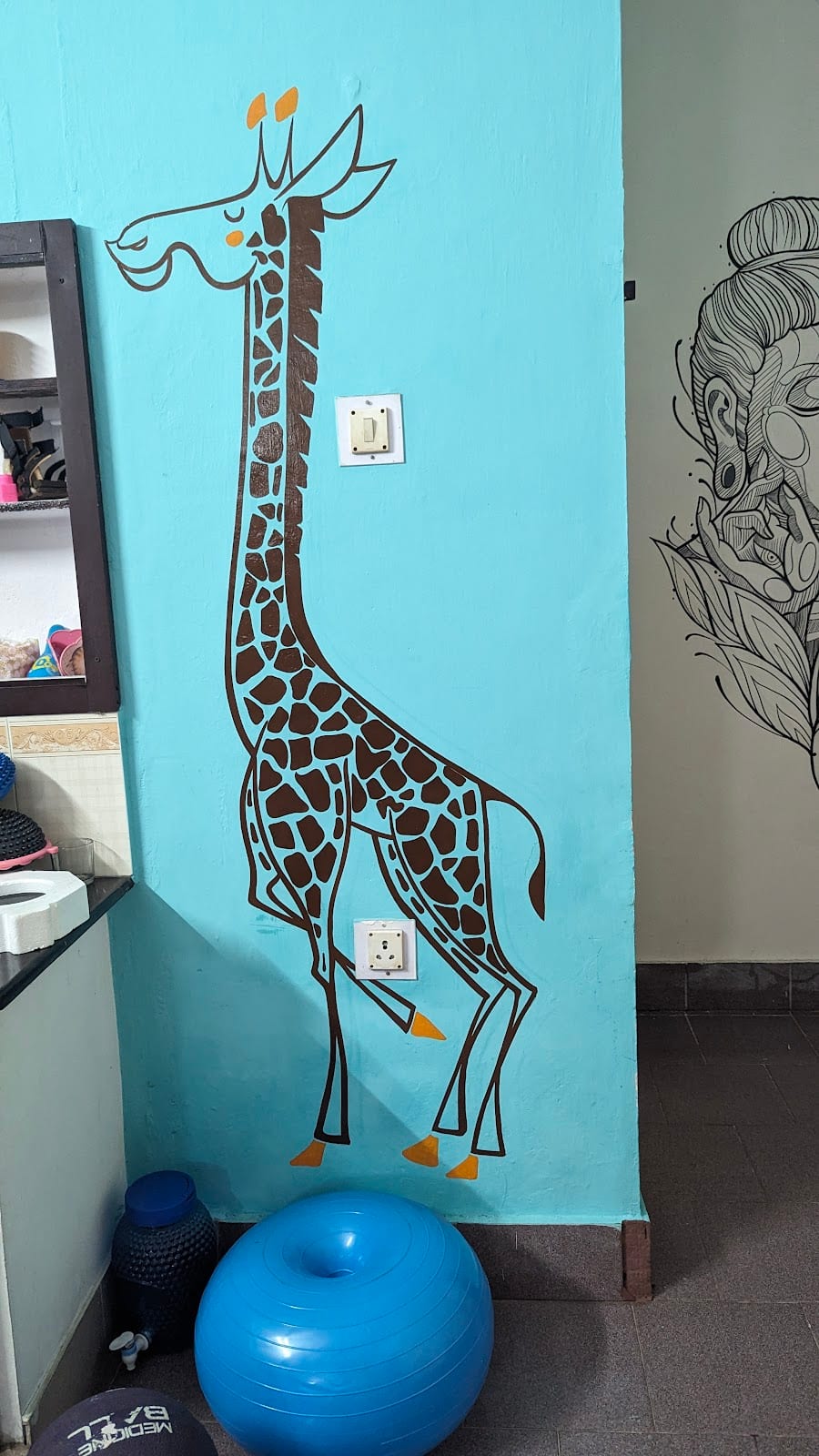 Sensory and exercise corner with a giraffe wall mural, therapy gym balls and a medicine ball