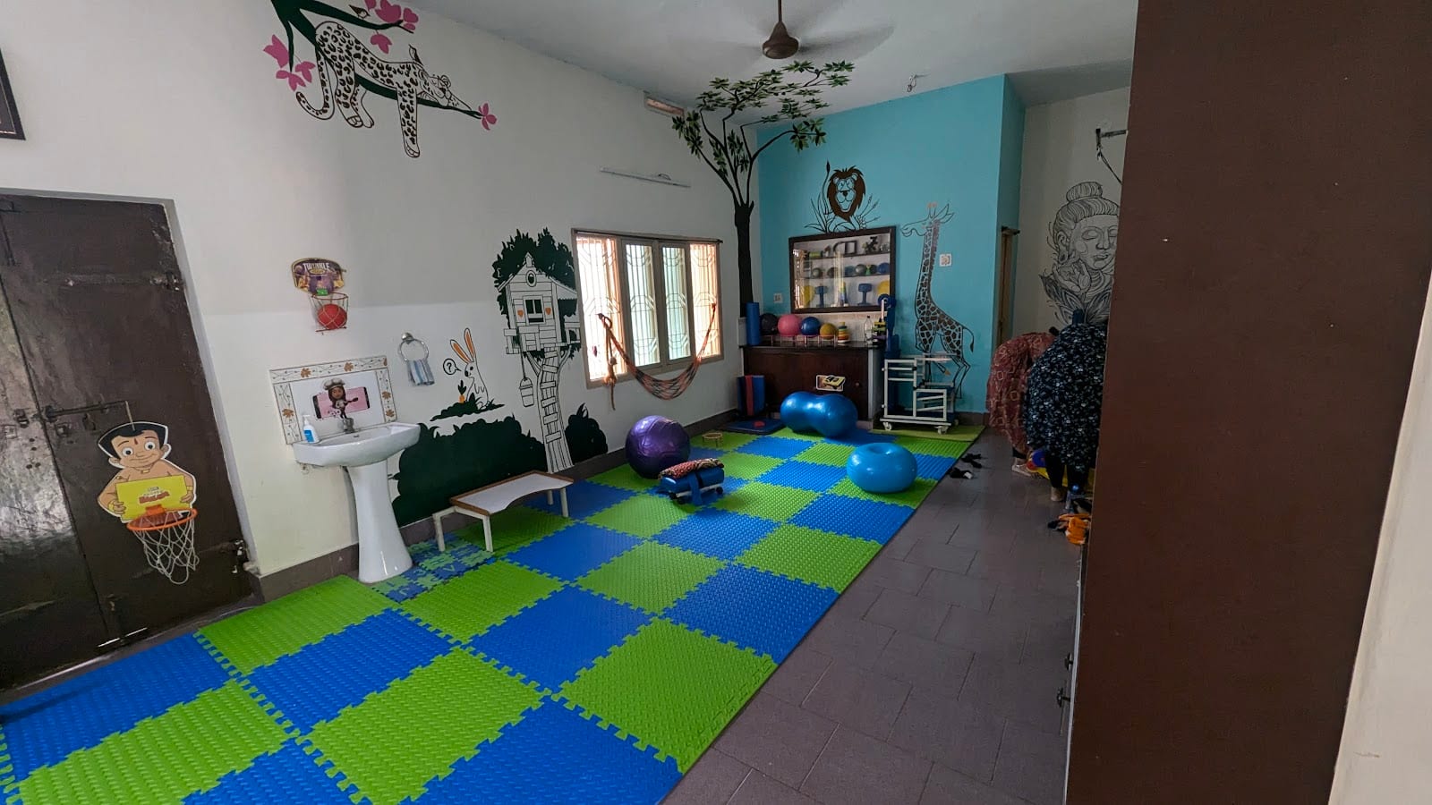 The pediatric physiotherapy hall at Thera360 in Kakinada, with a colourful floor mat, wall murals and exercise equipment