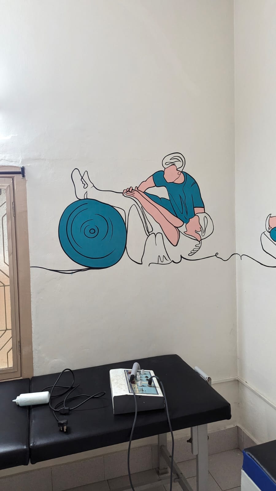 Treatment room at Thera360 with a therapy plinth and an electrotherapy unit beside an exercise wall illustration